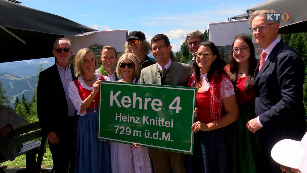 Personen, die eine Tafel hochhalten mit der Aufschrift Kehre 4 Heinz Knittel 729m ü.d.M.